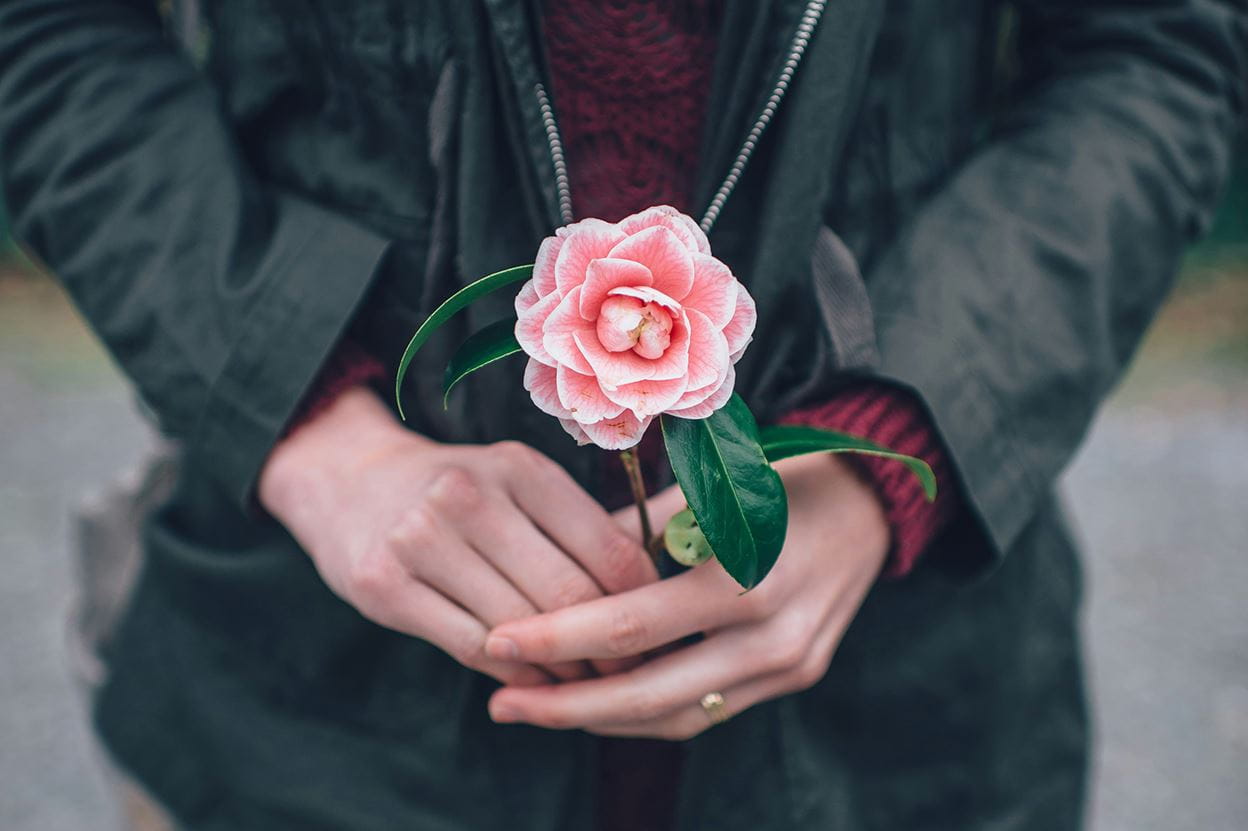 A woman holding a pink flower