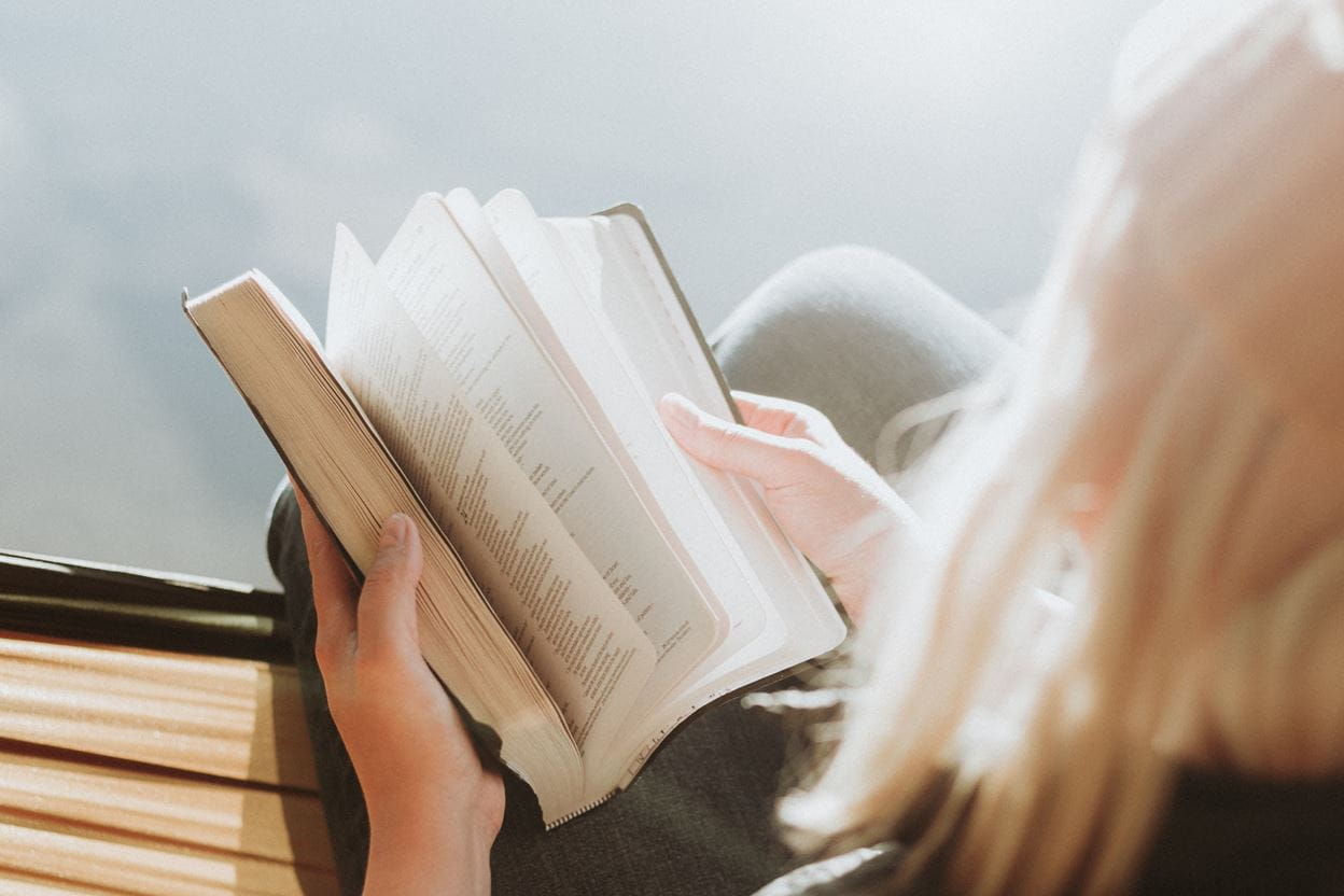 A woman holding a Bible, preparing to read a daily devotional.