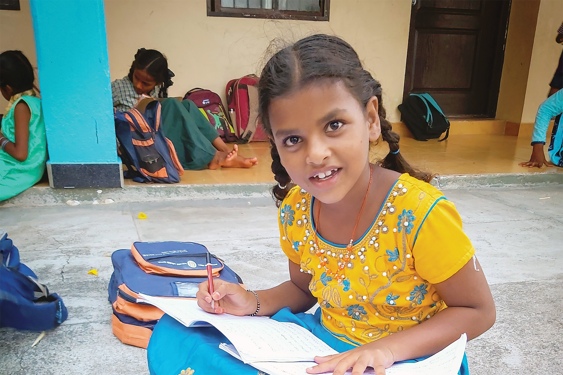 Anushka smiling, sitting outside, completing her school work